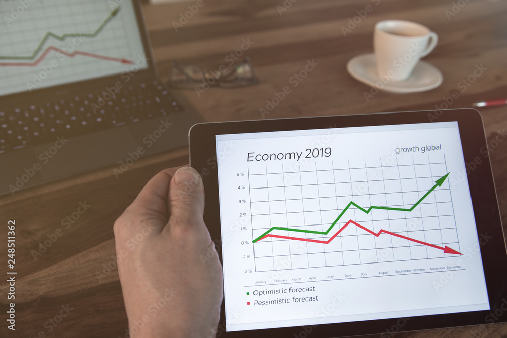 Man sitting at the table with a tablet in his hand. Economic data is displayed. Man sitting at the table with a tablet in his hand. Economic data is displayed.