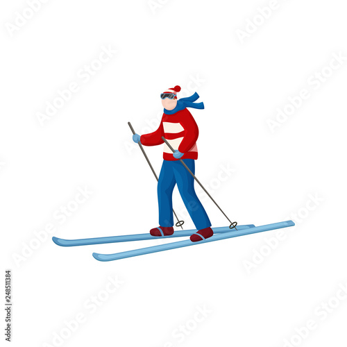 Skier in a ski suit with flying scarf in the wind is ready to descend from the mountain