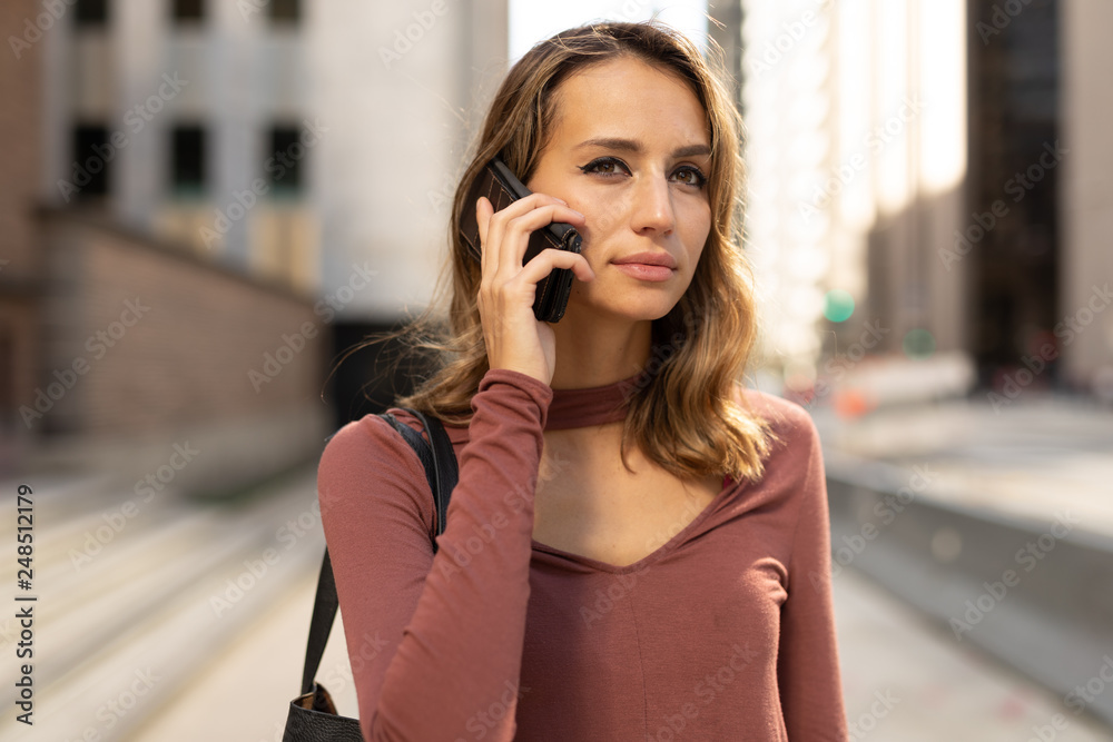 Young woman in city walking talking on cell phone Young woman in city walking talking on cell phone