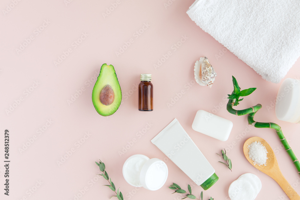 Top view of avocado oil for spa beauty treatment use. Bottle of oil, green leaves and bamboo, white towel and fresh avocado on pink background, flatlay Top view of avocado oil for spa beauty treatment use. Bottle of oil, green leaves and bamboo, white towel and fresh avocado on pink background, flatlay
