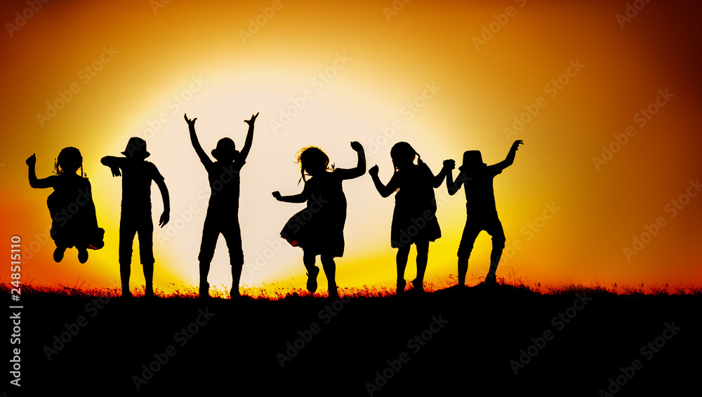 Silhouette of happy children boys and girls jumping and dancing in sunset sky evening time background as successful, happiness and careless concept