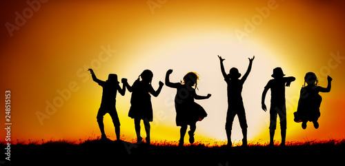 Silhouette of happy children boys and girls jumping and dancing in sunset sky evening time background as successful, happiness and careless concept