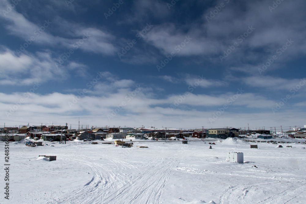 View of Rankin Inlet, a remote arctic community in Nunavut with blue skies and snow on the ground