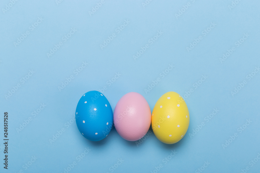 Colorfull easter eggs in nest on blue pastel color background with space.