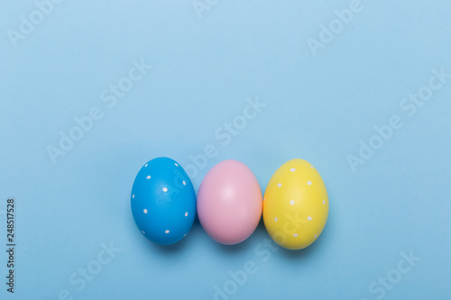 Colorfull easter eggs in nest on blue pastel color background with space.