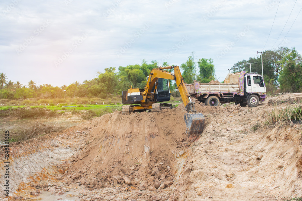 Yellow excavator machine loading soil into a dump truck at construction site