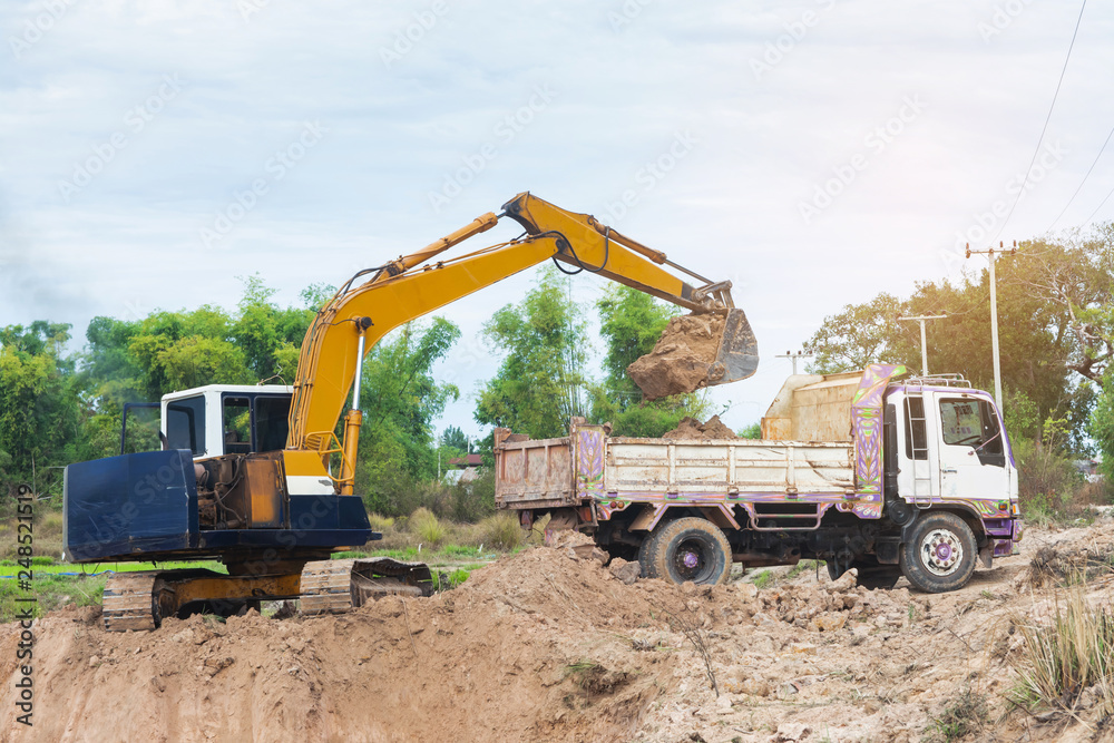 Yellow excavator machine loading soil into a dump truck at construction site Yellow excavator machine loading soil into a dump truck at construction site