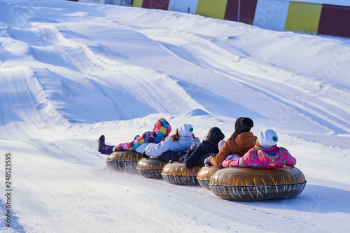A group of friends riding tubing from a snowy mountain in winter