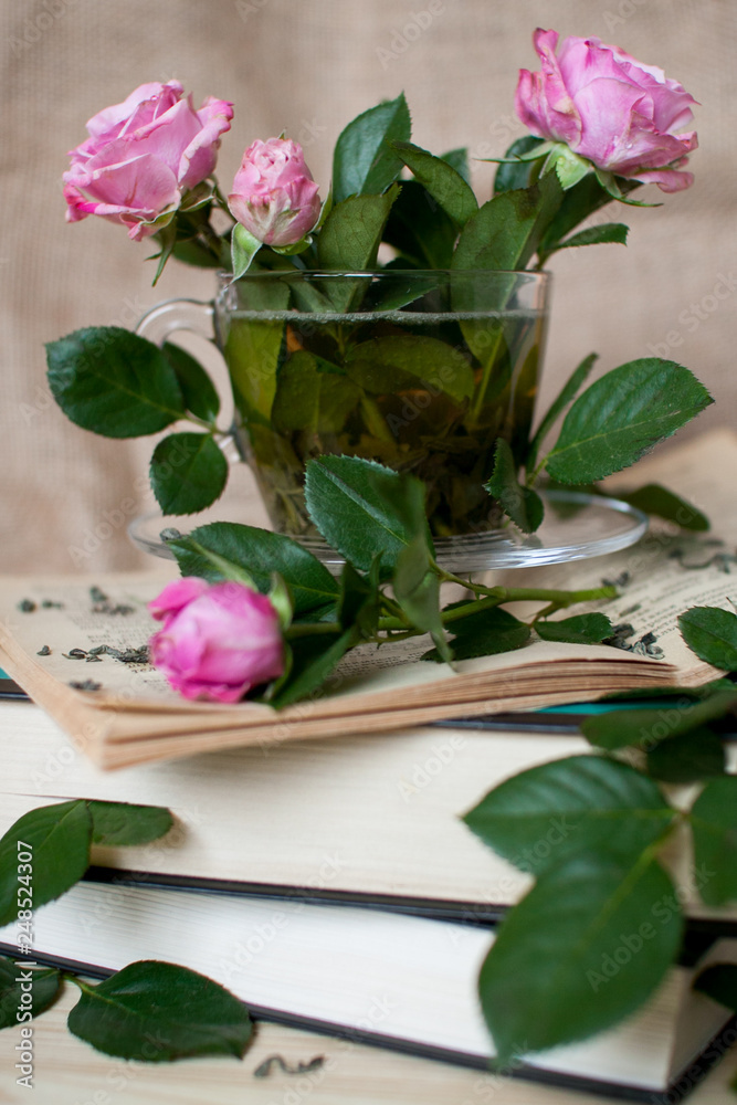cup with tea and pink roses on an open book