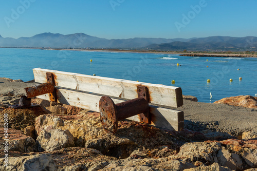 Rusty and broken wooden bench by the sea photo