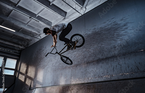 Bmx freestyle. Young BMX making tricks on his bicycle in skatepark indoors