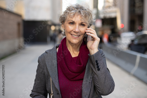 Mature woman in city walking talking on cell phone