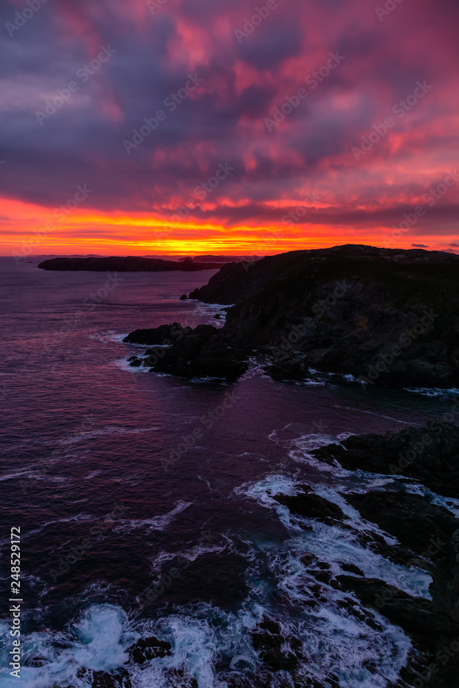 Striking seascape view on a rocky Atlantic Ocean Coast during a colorful sunrise. Taken at Crow Head, North Twillingate Island, Newfoundland and Labrador, Canada.