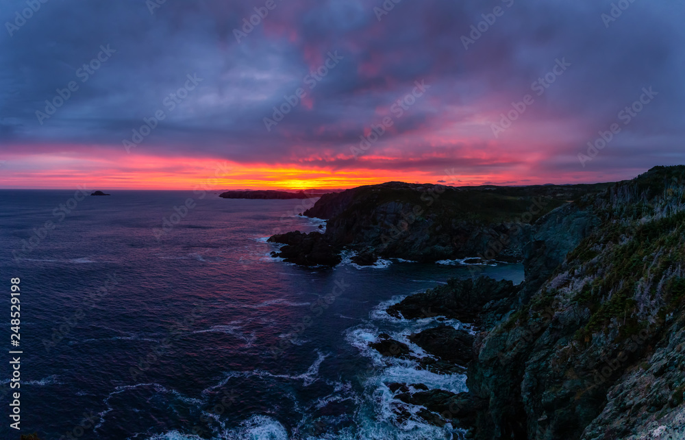 Striking seascape view on a rocky Atlantic Ocean Coast during a colorful sunrise. Taken at Crow Head, North Twillingate Island, Newfoundland and Labrador, Canada.