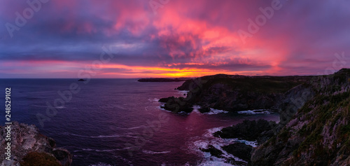 Striking panoramic seascape view on a rocky Atlantic Ocean Coast during a colorful sunrise. Taken at Crow Head, North Twillingate Island, Newfoundland and Labrador, Canada.