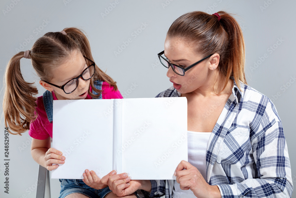 Smiling beautiful woman and her daughter in glasses with book Smiling beautiful woman and her daughter in glasses with book