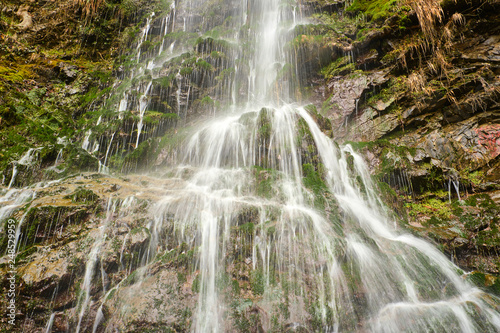 Small slow motion waterfall cascading over rocks with beautiful lush vegetation
