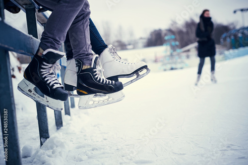 Couple wearing ice skates sitting on a guardrail. Dating in an ice rink. photo