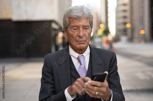 Senior businessman in city walking texting on cell phone © blvdone