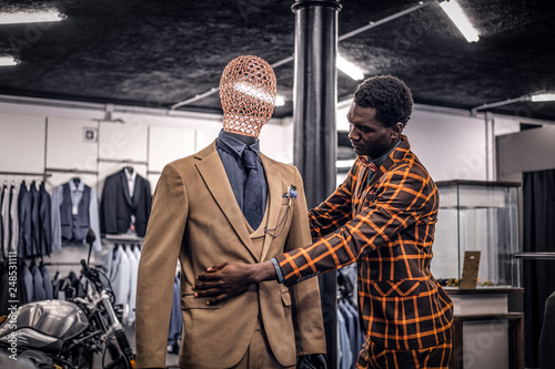 Stylish African-American man dressed in trendy elegant suit, working at classic menswear store.