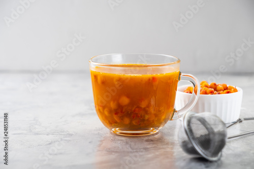 Colorful hot sea buckthorn tea with rosemary and fresh sea buckthorn berries on a grey table. Vitamin drink.