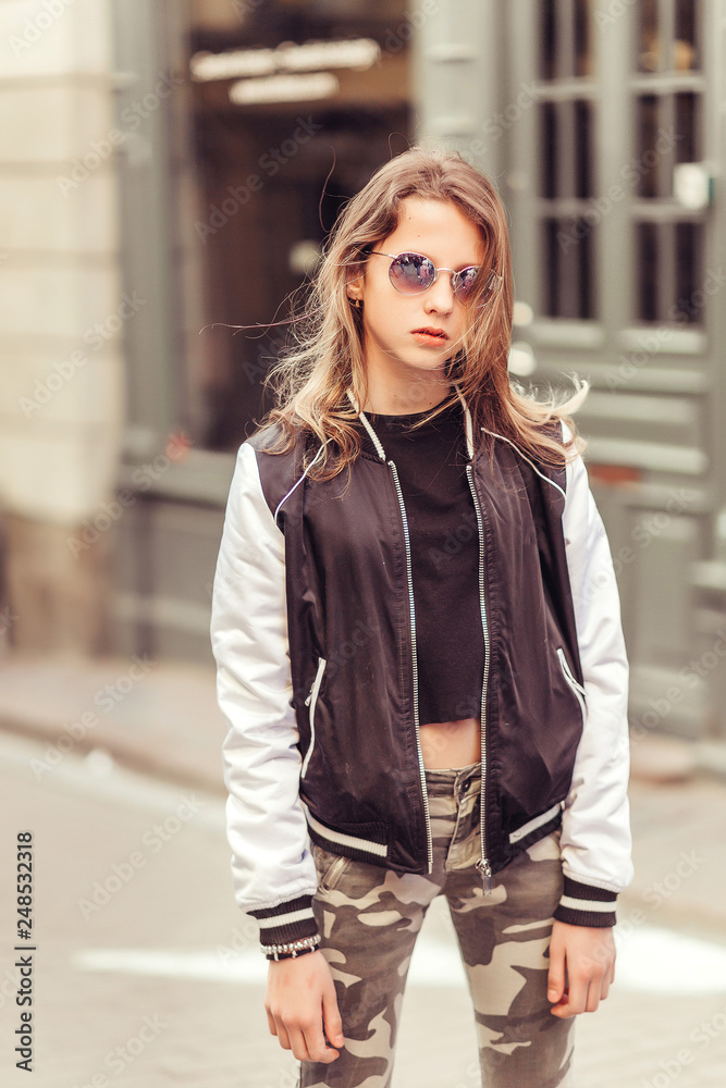 Young hipster modern girl model posing in sun glasses outdoors in the city center. Street style portrait, beauty, fashion, lifestyle concept Young hipster modern girl model posing in sun glasses outdoors in the city center. Street style portrait, beauty, fashion, lifestyle concept