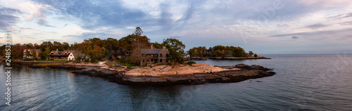 Panoramic seascape view of beautiful homes on a rocky Atlantic Coast during a vibrant sunset. Taken in New Haven, Connecticut, United States. photo