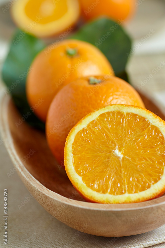 Oranges in a wooden bowl with leaves Oranges in a wooden bowl with leaves