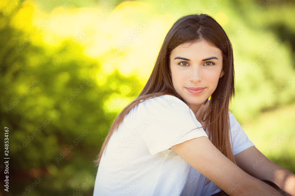 Pretty young woman sitting at the park in the summer Pretty young woman sitting at the park in the summer