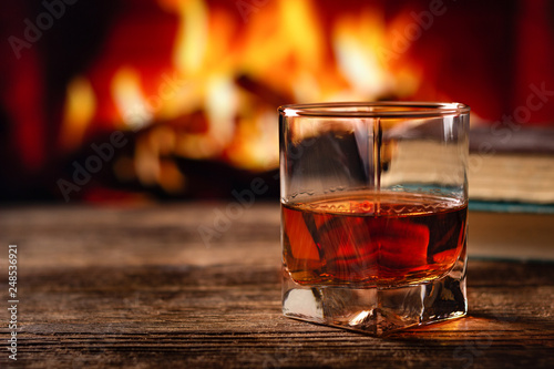 Fototapeta Naklejka Na Ścianę i Meble -  Glass of cognac or whiskey. Blur burning fireplace background.