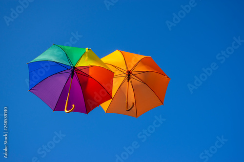 Group of flying umbrellas isolated on blue background  ready for the rain  wallpaper background  bright various colors