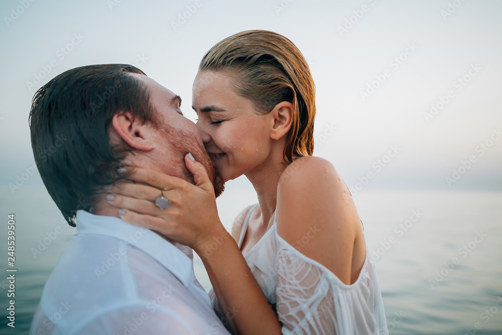 Two lovers on the beach kissing and hugging in the hot summer sun on a sandy beach
