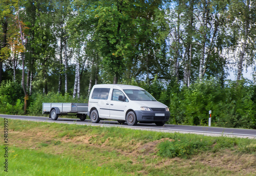 Car with a Trailer moves on a country road © Yuri Bizgaimer