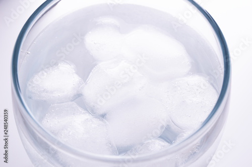 water with ice cubes in glass. white background