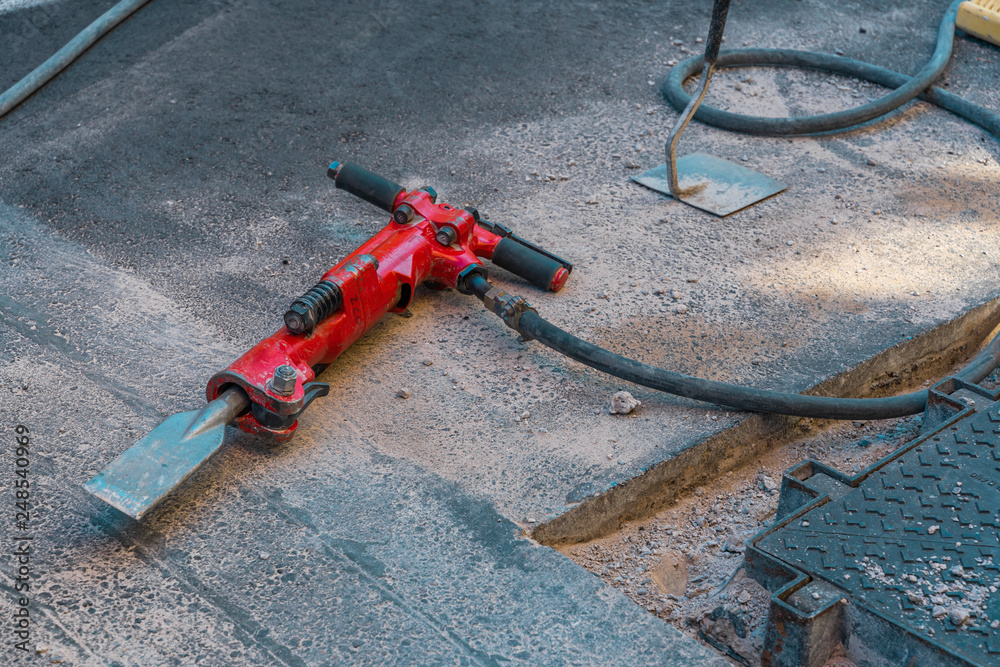 Red jackhammer at construction site.
