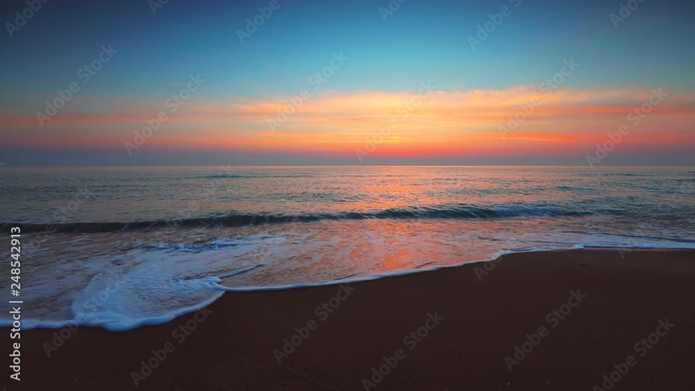Sunrise over the sea and beach. Waves washing the sand.