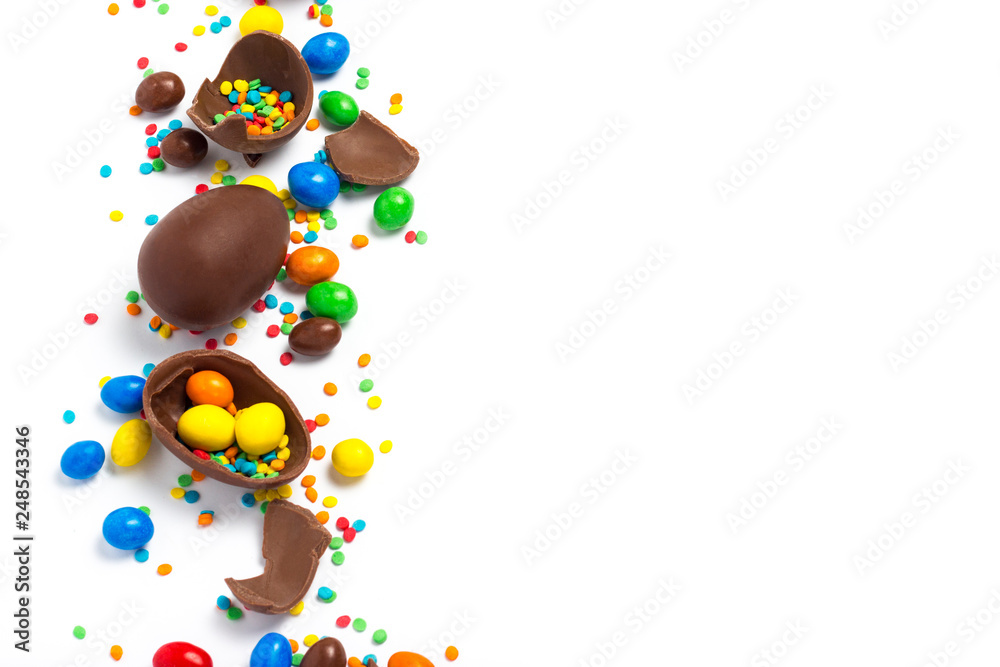 Broken and whole chocolate Easter eggs, multicolored sweets on white background. Concept of celebrating Easter, Easter decorations, search for sweets for Easter Bunny. Flat lay, top view. Copy Space