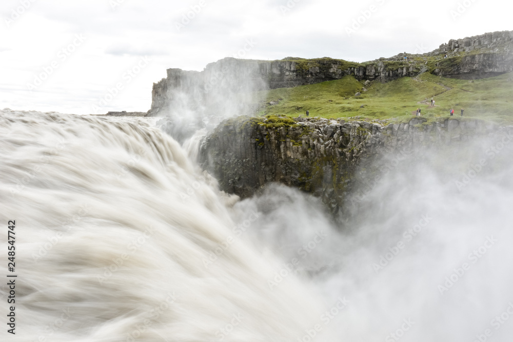 Fresh clean Dettifoss waterfall  in Iceland in  summer with loads of water flowing and mist, water in motion blur