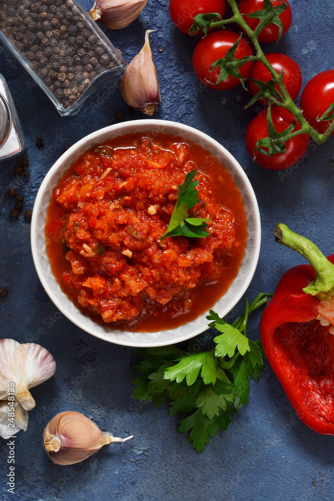 Tomato sauce with peppers, spices and herbs on the kitchen table. View from above.