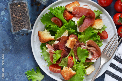 Salad with prosciutto  cherry tomatoes  bread crisps on the kitchen table. View from above.