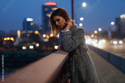 Woman standing on bridge in the ligths of night city