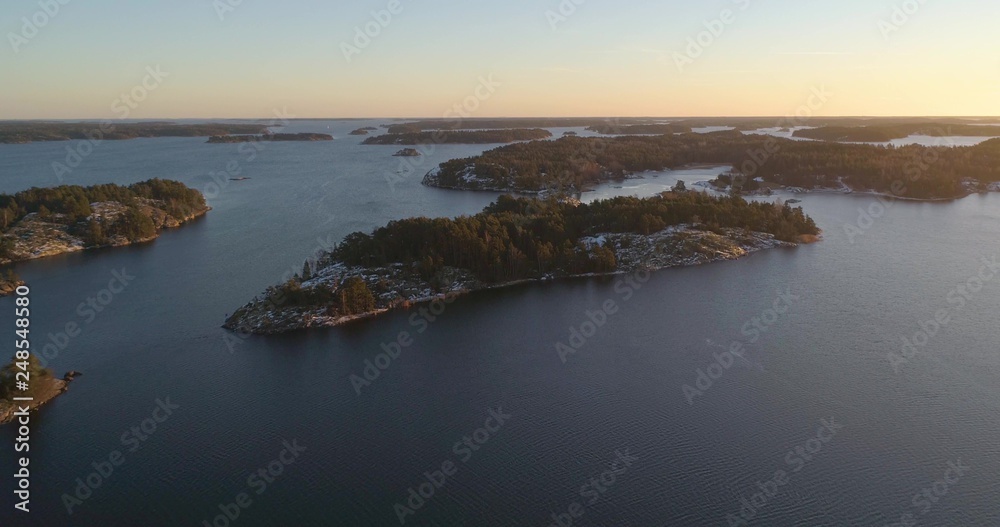 Drone shot, towards frosty and snowy islands, on the gulf of Finland, at sunset, on a sunny, cold, autumn evening, Varsinais-suomi, Finland
