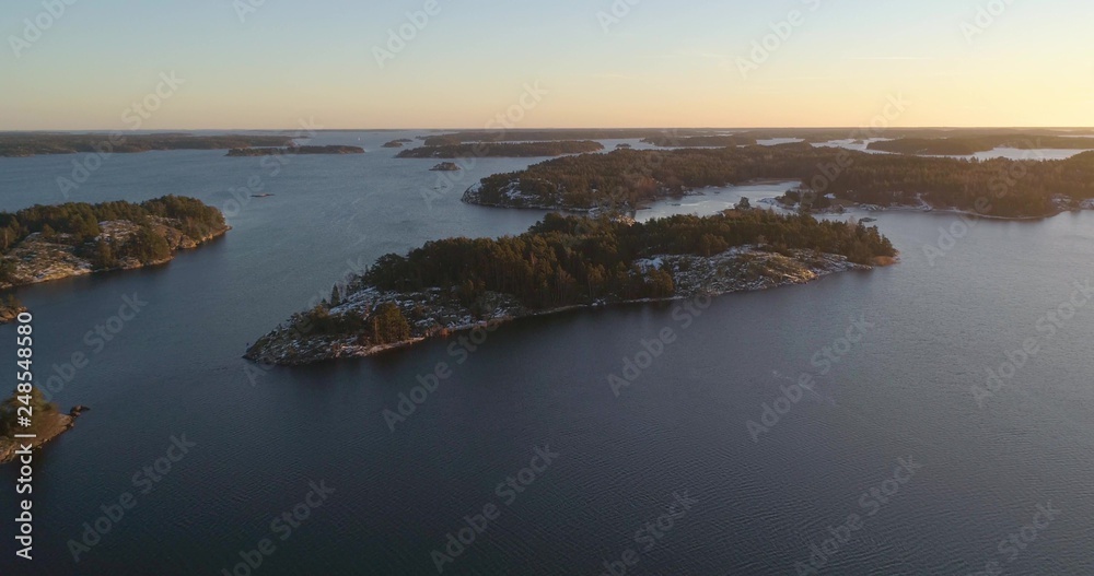 Drone shot, towards frosty and snowy islands, on the gulf of Finland, at sunset, on a sunny, cold, autumn evening, Varsinais-suomi, Finland Drone shot, towards frosty and snowy islands, on the gulf of Finland, at sunset, on a sunny, cold, autumn evening, Varsinais-suomi, Finland