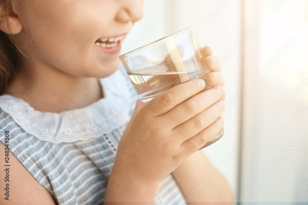 Cute little girl holding glass of fresh water at home, closeup Cute little girl holding glass of fresh water at home, closeup