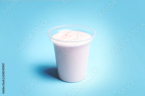 Plastic cup with creamy yogurt on color background