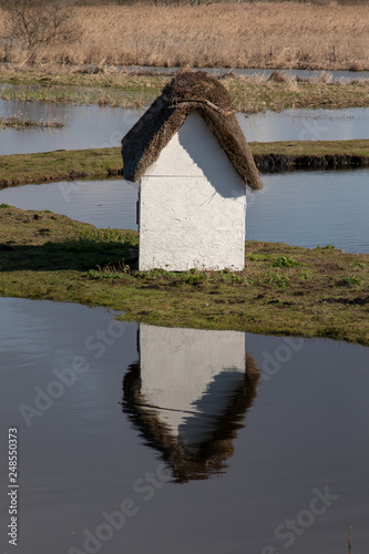 Old whitewashed house reflected in a lake photo