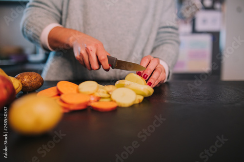 a person cutting potatoes and sweet potatoes in a nice kitchen