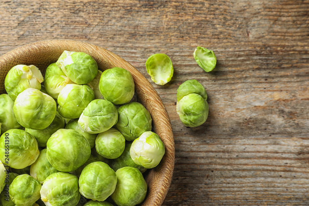 Bowl of fresh Brussels sprouts on wooden background, top view with space for text Bowl of fresh Brussels sprouts on wooden background, top view with space for text