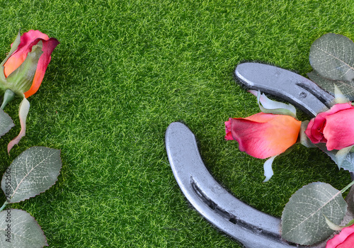 Red silk roses, a horseshoe and artificial green grass for the running of the thoroughbred race called the Kentucky Derby. Copy space