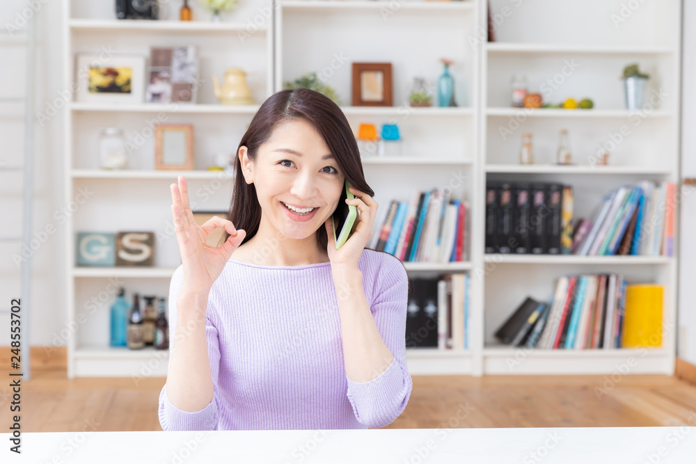 部屋で電話をする女性 部屋で電話をする女性